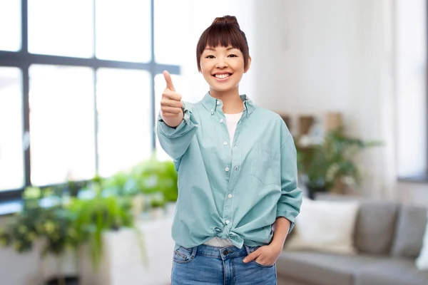 Szczęśliwy Azji kobieta pokazując kciuki w górę nad dom — Zdjęcie stockowe