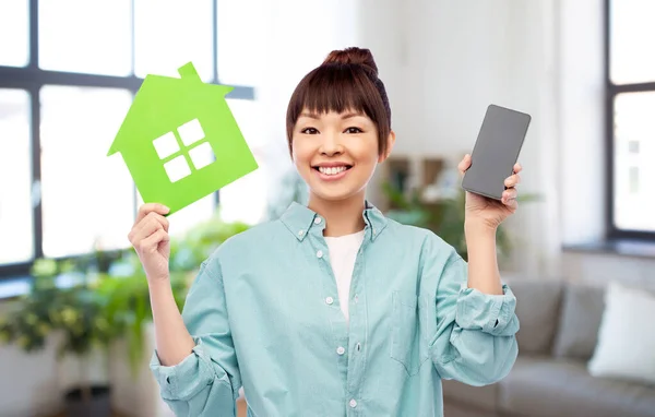 Glimlachende aziatische vrouw holding green house — Stockfoto