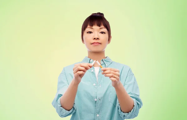 Mujer asiática frenando cigarrillo sobre verde — Foto de Stock