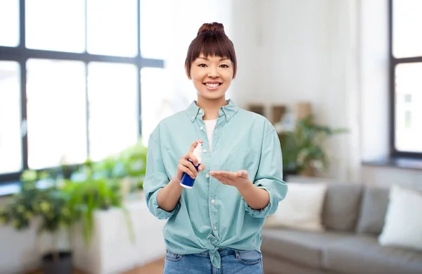 Счастливая улыбающаяся азиатка с помощью средства для дезинфекции рук — стоковое фото