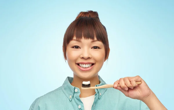 Azjatycka kobieta z pastą do zębów na drewnianej szczoteczce — Zdjęcie stockowe
