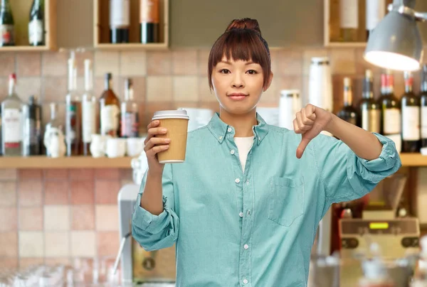 Mulher asiática com café mostrando polegares para baixo no bar Fotos De Bancos De Imagens