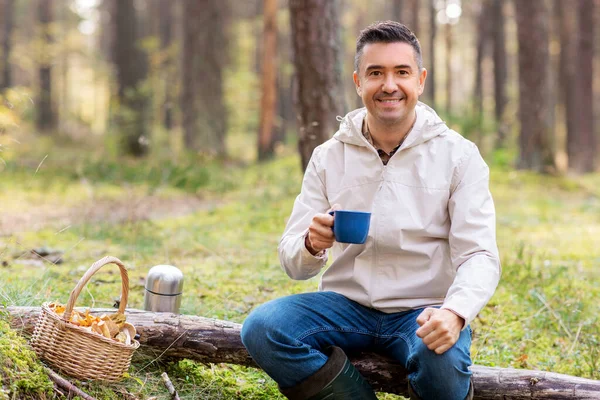Homme avec panier de champignons boissons thé en forêt — Photo