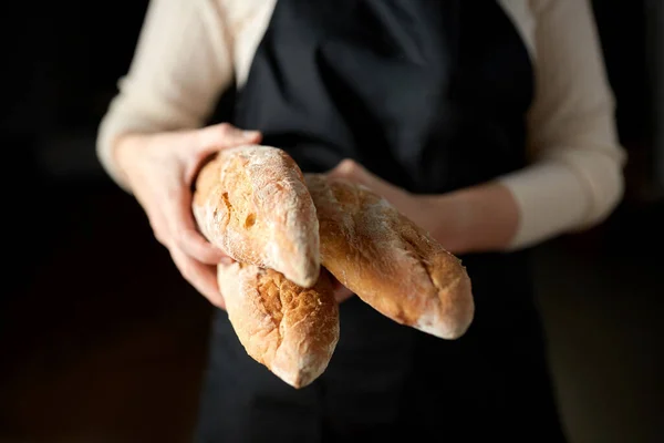 Close up of female baker holding baguette bread — Stock Photo, Image