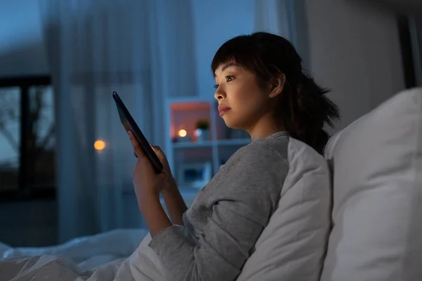 Aziatische vrouw met tablet pc in bed thuis 's nachts — Stockfoto