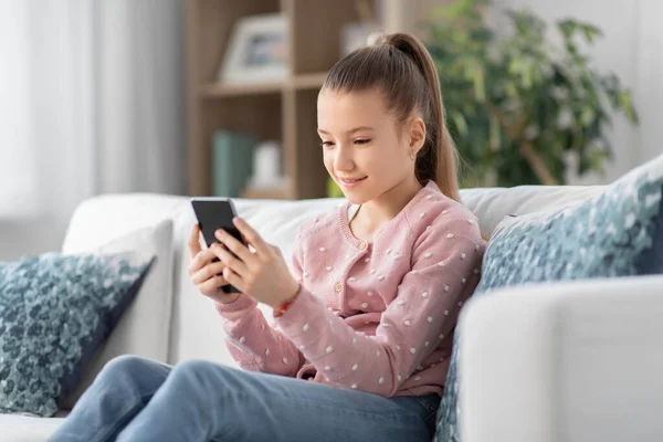 Felice sorridente bambina con smartphone a casa — Foto Stock