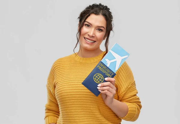 Mujer feliz con billete de avión y pasaporte de inmunidad — Foto de Stock