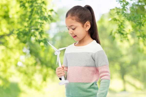 Girl with toy wind turbine over natural background — Stock Photo, Image