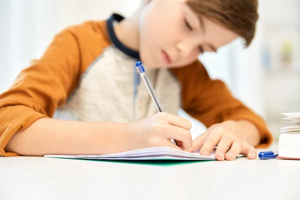 Estudiante con escritura de libros a cuaderno en casa —  Fotos de Stock