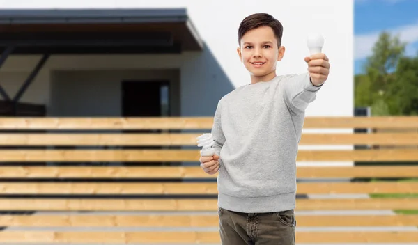 Boy comparing different light bulbs over house Royalty Free Stock Images