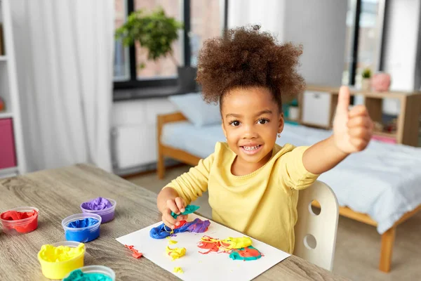 Маленькая девочка с моделью глины играет дома — стоковое фото