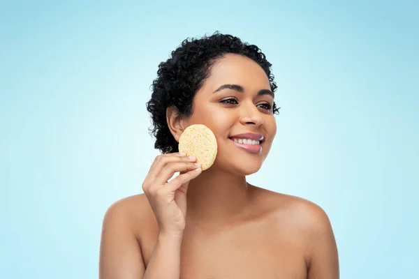 Mujer joven limpiando la cara con esponja exfoliante — Foto de Stock