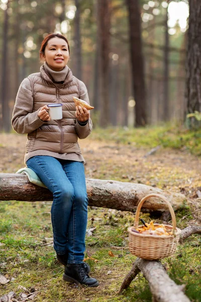 キノコを持つ女性はお茶を飲んで森の中で食べる — ストック写真