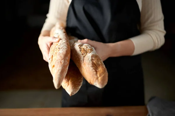 Close up of female baker holding baguette bread — Stock Photo, Image