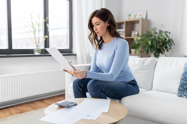 Mujer con papeles y calculadora en casa — Foto de Stock