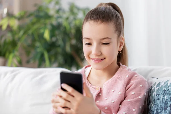 Glücklich lächelndes kleines Mädchen mit Smartphone zu Hause — Stockfoto