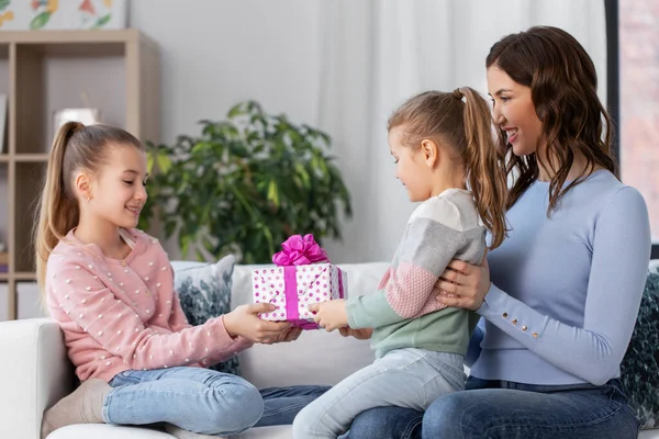 Chica dando regalo a la hermana menor en casa —  Fotos de Stock