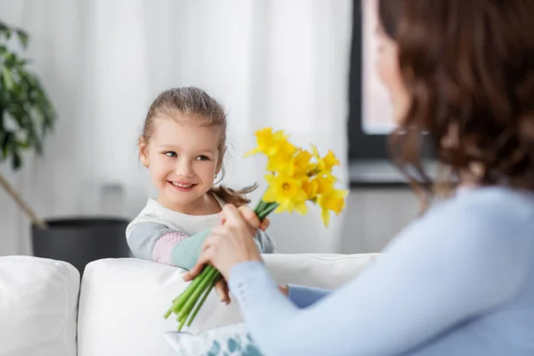 Šťastná dcera dává narcisy květiny na matku — Stock fotografie