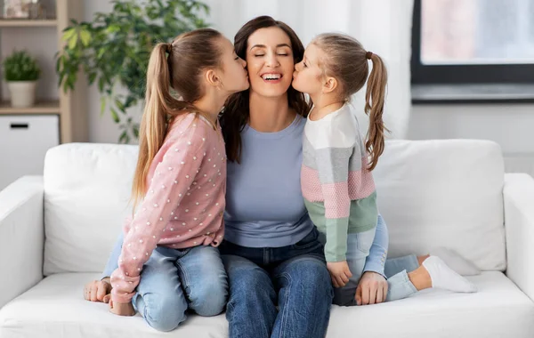 Счастливая мать и две дочери целуют ее дома — стоковое фото