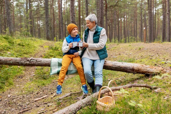 Grand-mère avec petit-fils boire du thé dans la forêt — Photo