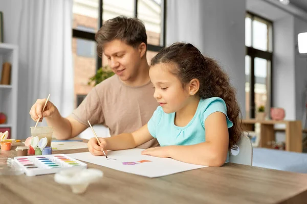 Счастливый отец с маленькой дочкой рисует дома — стоковое фото