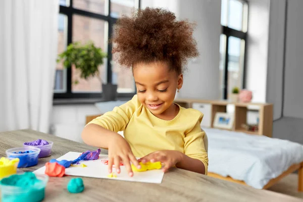 Klein meisje met modelleren klei spelen thuis — Stockfoto