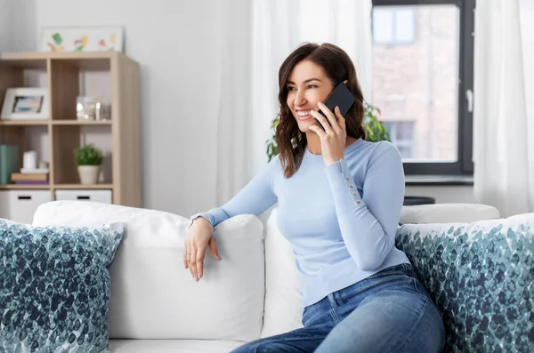 Lächelnde Frau, die zu Hause mit dem Smartphone telefoniert — Stockfoto