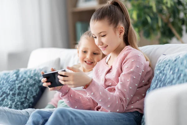 Meninas ou irmãs felizes com telefone em casa — Fotografia de Stock