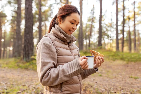 Kobieta z grzybami pije herbatę i je w lesie — Zdjęcie stockowe
