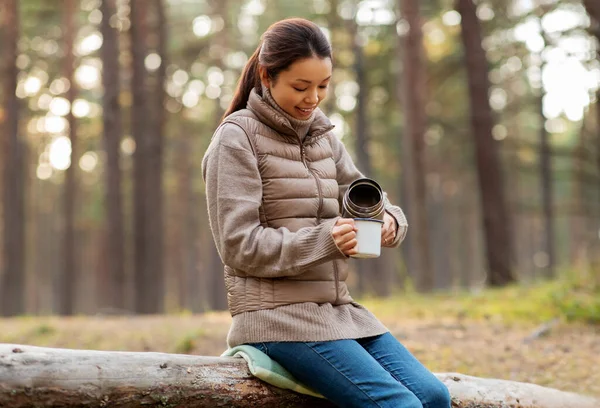 Termoslu Asyalı kadın ormanda çay içiyor. — Stok fotoğraf