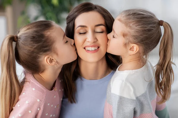 幸せな母親と2人の娘が家でキスして — ストック写真