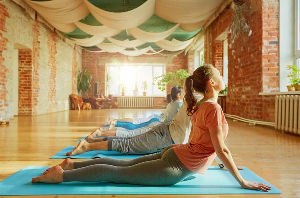 Groupe de personnes faisant du yoga pose cobra au studio — Photo