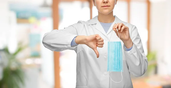 Female doctor with mask showing thumbs down — Stock Photo, Image