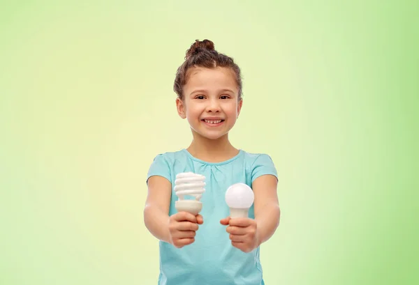 Chica sonriente comparando diferentes bombillas — Foto de Stock