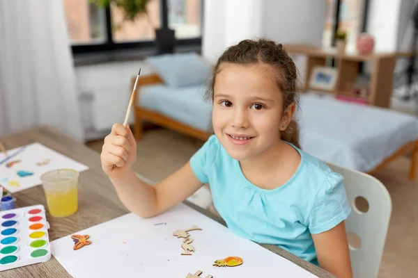 Küçük kız evde ahşap eşyalar boyuyor. — Stok fotoğraf