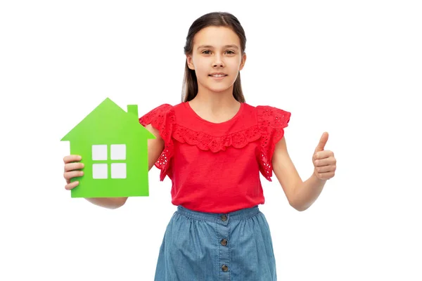 Ευτυχισμένο κορίτσι με πράσινο σπίτι εικονίδιο δείχνει τους αντίχειρες επάνω — Φωτογραφία Αρχείου