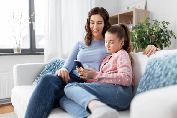 Mãe feliz e filha com smartphone em casa — Fotografia de Stock