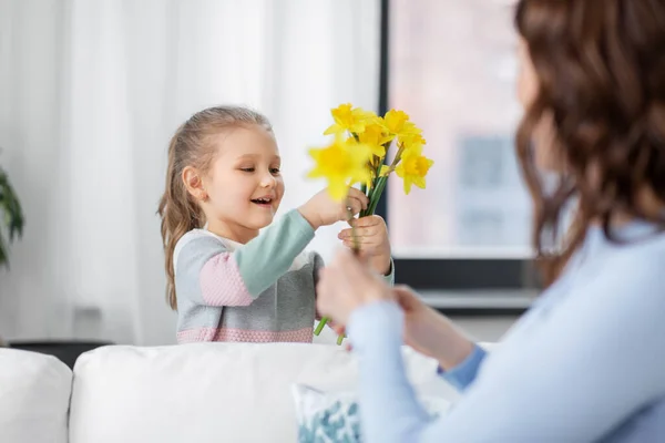 Šťastná dcera dává narcisy květiny na matku — Stock fotografie