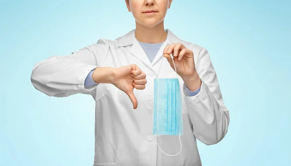 Női orvos maszkkal mutatja hüvelykujját lefelé — Stock Fotó