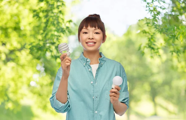 Asiática mulher segurando energia economizando lâmpada de iluminação — Fotografia de Stock
