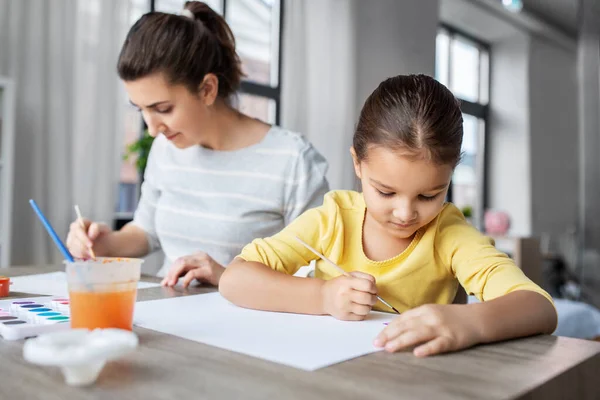 Мать с маленькой дочерью рисует дома — стоковое фото