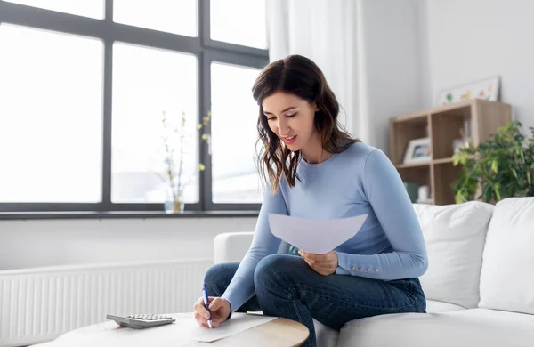 Woman with papers and calculator at home — Stock Photo, Image
