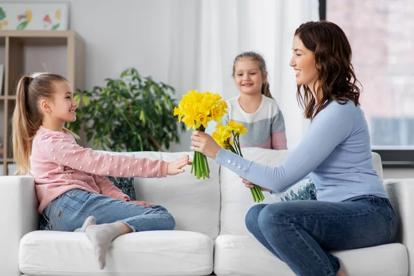 Töchter geben Narzissenblumen an glückliche Mutter — Stockfoto
