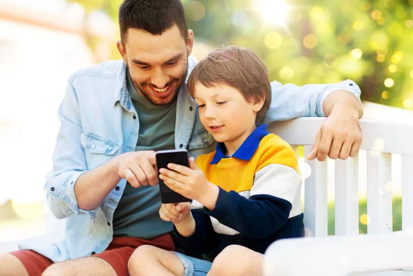 Pai e filho com smartphone no parque — Fotografia de Stock