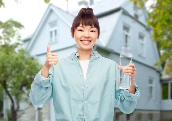 Heureux asiatique femme tenant bouteille en verre avec de l eau — Photo