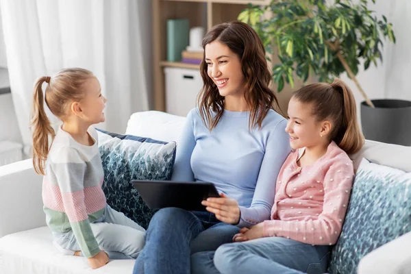 Mãe feliz e filhas com tablet pc em casa — Fotografia de Stock