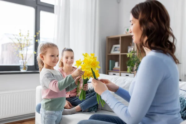 Filhas dando flores de narciso para mãe feliz — Fotografia de Stock