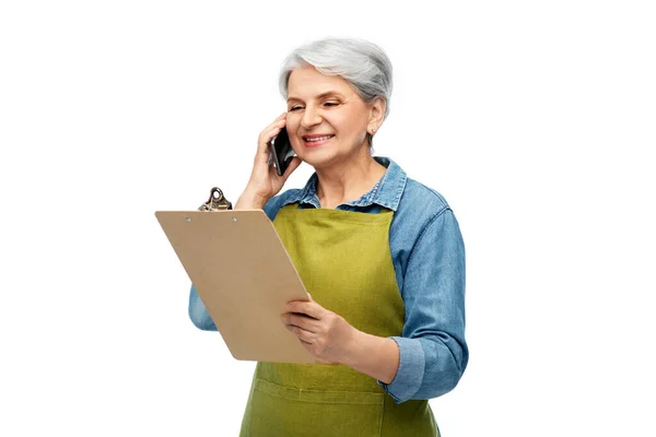 Oude vrouwelijke tuinman met klembord oproepen op telefoon — Stockfoto