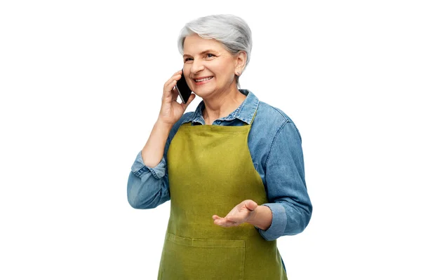Старша жінка в садовому фартусі телефонує на смартфон — стокове фото