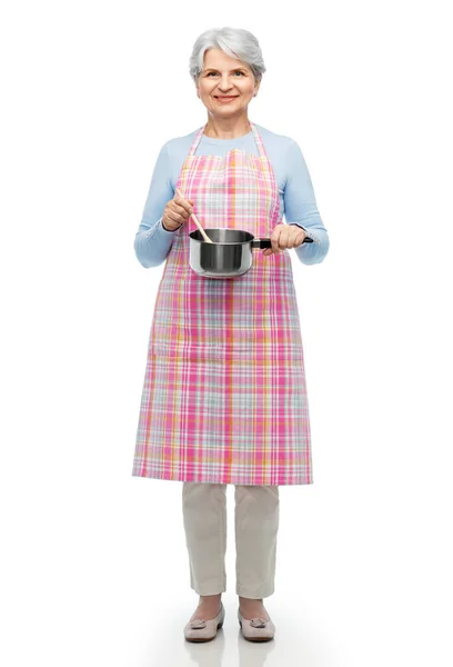 Senior vrouw in schort met pot koken voedsel — Stockfoto